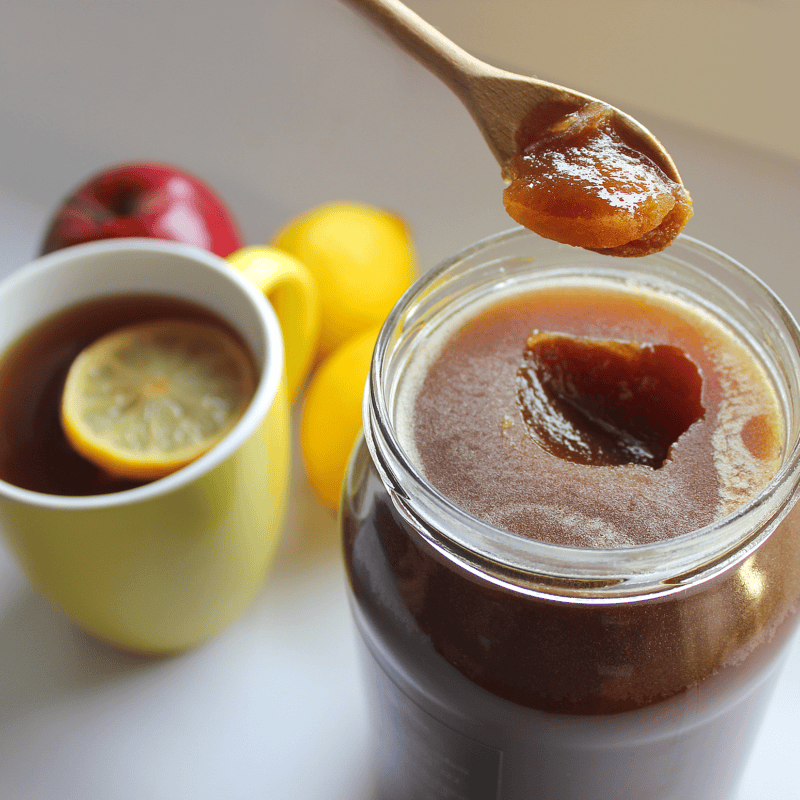 Miód naturalny w słoiku Miód naturalny w słoiku z łyżeczką, obok cytryna i jabłko.